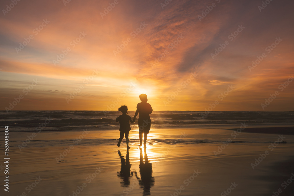 Happy children running on beach at sunset time