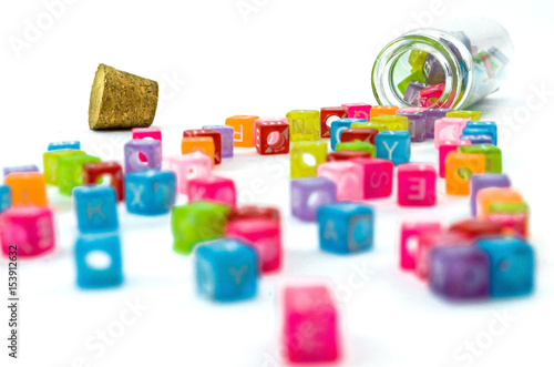 Colourful small cubes with characters random scattered from the vial isolated on white background. Word education concept.