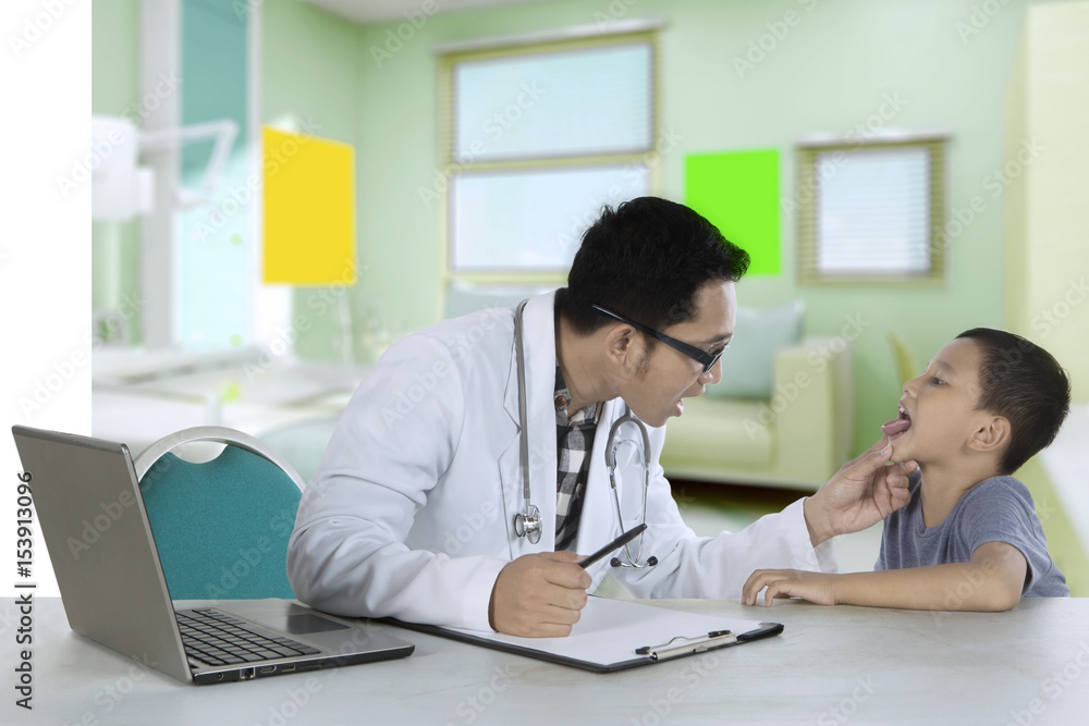 Pediatrician checking tongue of a patient in clinic Pediatrician checking tongue of a patient in clinic