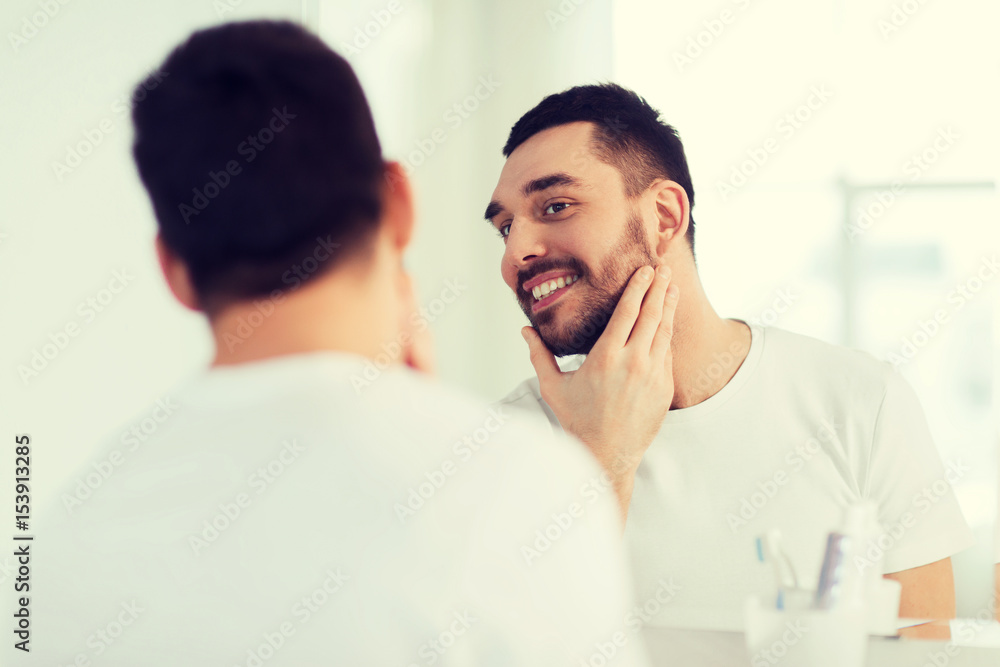 happy young man looking to mirror at home bathroom happy young man looking to mirror at home bathroom