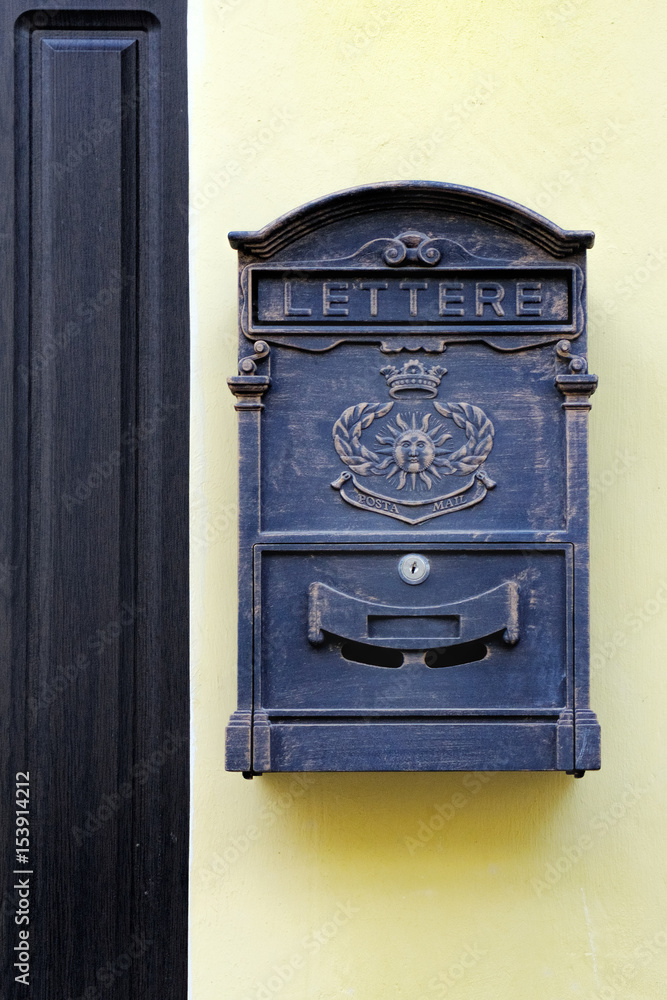 Metal mailbox in antique style hanging near the front door of the house on yellow wall Metal mailbox in antique style hanging near the front door of the house on yellow wall
