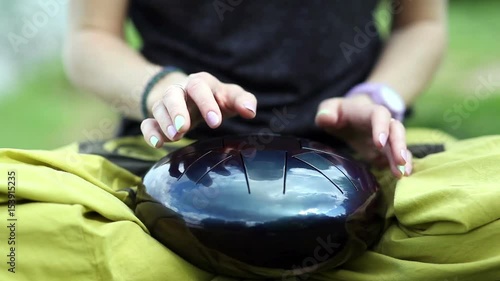 Woman is playing on the steel tongue drum in the park photo