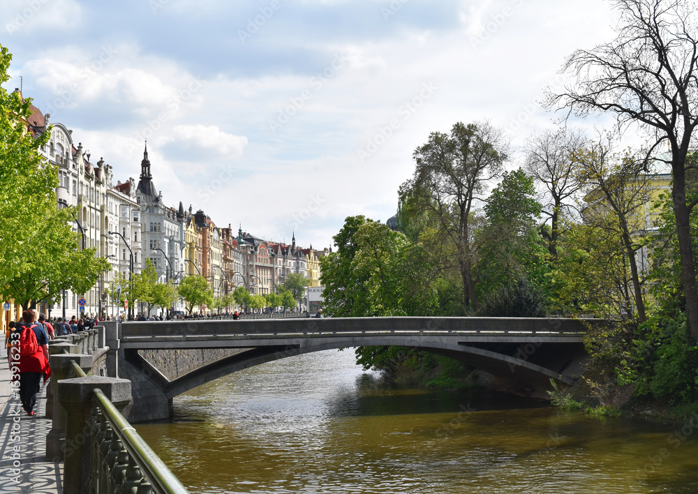 A little bridge on a river with colorful buildings in Prague city center, in Czech Republic