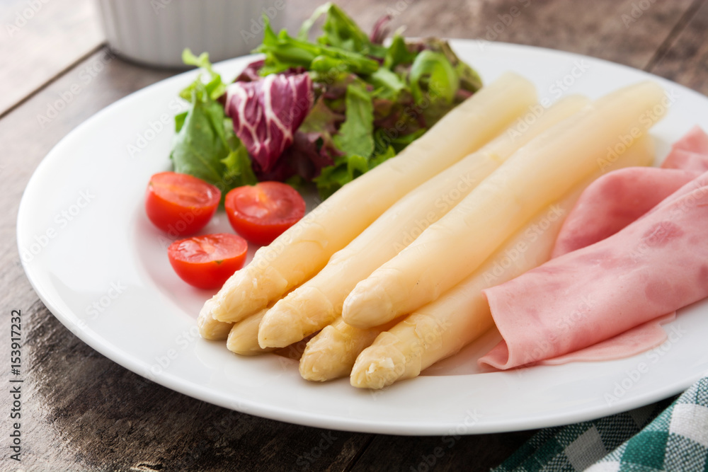 White asparagus with salad and ham on wooden background
White asparagus with salad and ham on wooden background
