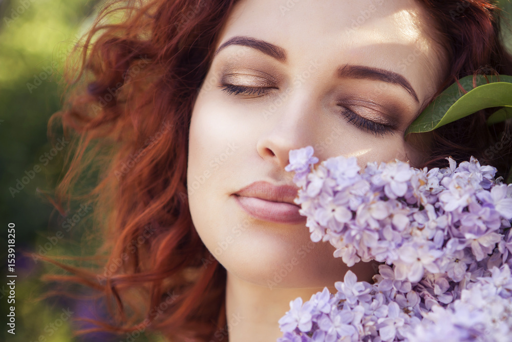 Beautiful red haired woman with fresh flawless skin and curly hairstyle in dress in park near flowers. Sensual, sexy, soft emotion. Sunny day Beautiful red haired woman with fresh flawless skin and curly hairstyle in dress in park near flowers. Sensual, sexy, soft emotion. Sunny day