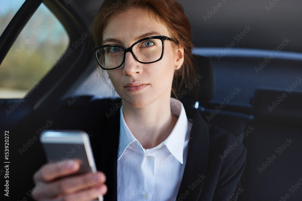 Mid-age business woman working while being in the car Mid-age business woman working while being in the car