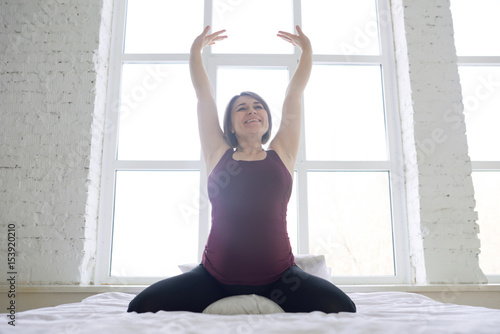 Pregnant woman doing stretching exercises in bed