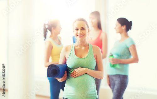 happy pregnant woman with mat in gym
