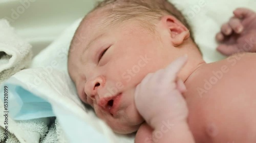 doctor puts a newborn with a clamp on the umbilical cord photo