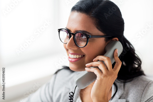 smiling businesswoman calling on phone at office