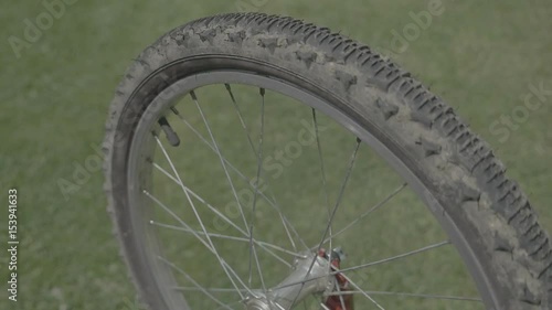 Bicycle wheel cover. Bicycle tire. Rotating spinning wheel with field sample. Glossy metallic wheel stringing on a grassy background. Static day stabilized v-log slow motion footage.