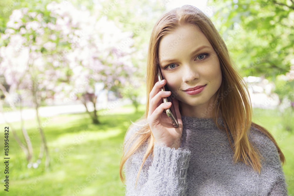 Beautiful red hair ginger slim young woman with fresh skin in casual outfit, posing with flowers. Sunny summer day in park (nature). Daylight Beautiful red hair ginger slim young woman with fresh skin in casual outfit, posing with flowers. Sunny summer day in park (nature). Daylight