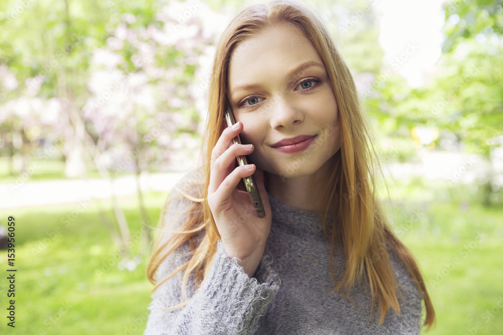 Beautiful red hair ginger slim young woman with fresh skin in casual outfit, making phone call. Sunny summer day in park (nature). Daylight Beautiful red hair ginger slim young woman with fresh skin in casual outfit, making phone call. Sunny summer day in park (nature). Daylight