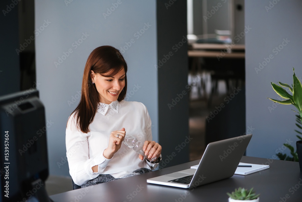 Young happy businesswoman holding a bottle of water in office Young happy businesswoman holding a bottle of water in office