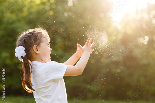 Adorable little girl, has happy fun with cheerful smiling face. Carefree child Running and jumping on green summer meadow, catching soap bubbles. Happiness, childhood and freedom concept.