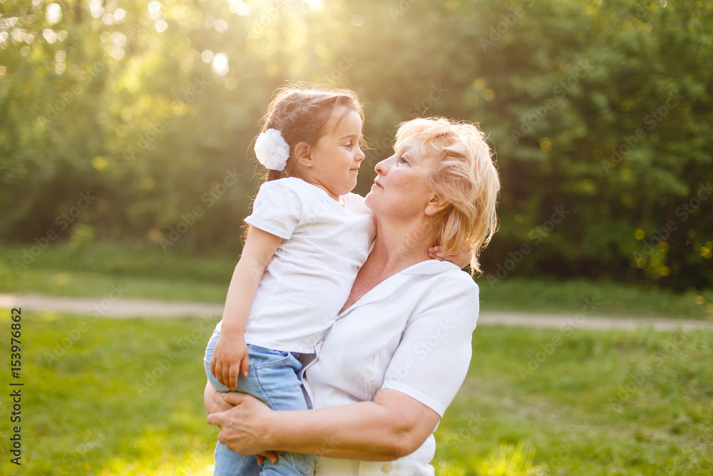 Fototapeta premium Grandmother hugging granddaughter legs and smiling.