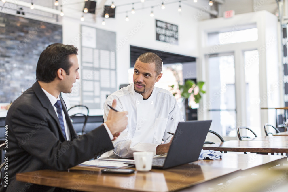 Businessman explaining with male chef in restaurant Businessman explaining with male chef in restaurant