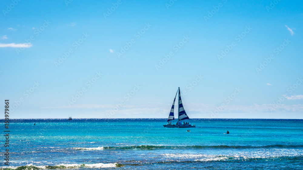 Obraz premium Sail Boat in the Pacific Ocean just off the coast at the famous Waikiki beach of the Hawaiian island of Oahu
