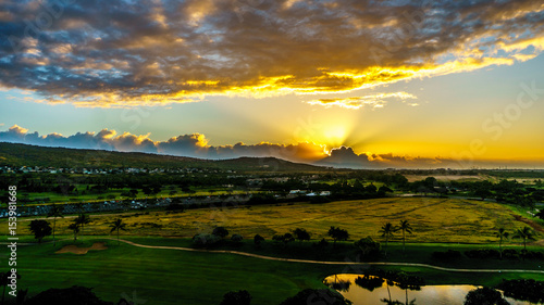 Sunrise over the horizon with sun peeking under dark morning clouds at the resort community of Ko Olina on the island of Oahu in the island state of Hawaii