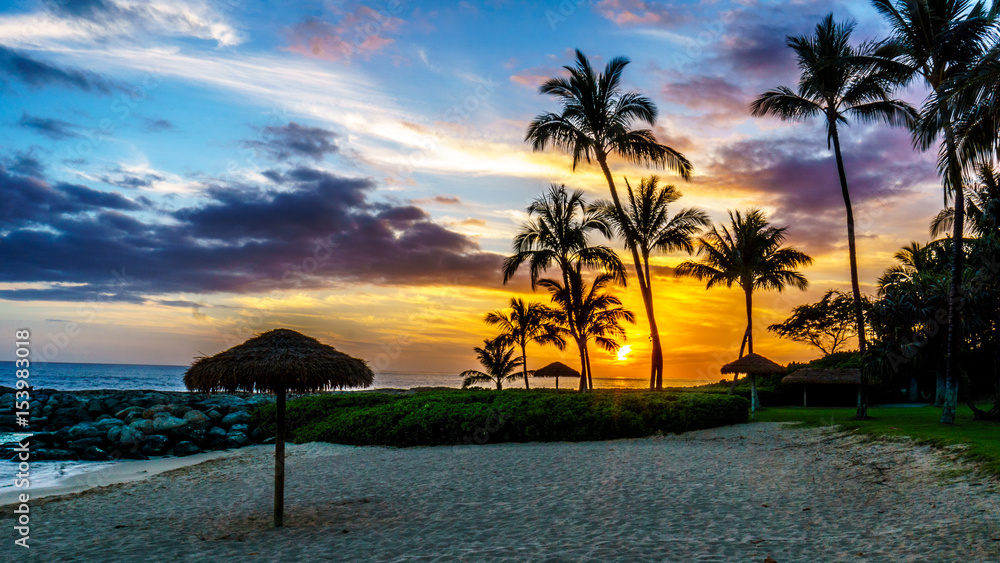 Obraz premium Sunset over the Lagoon and beach with Palm trees and colorful sky at the resort community of Ko Olina on the West Coast of the Hawaiian island of Oahu
