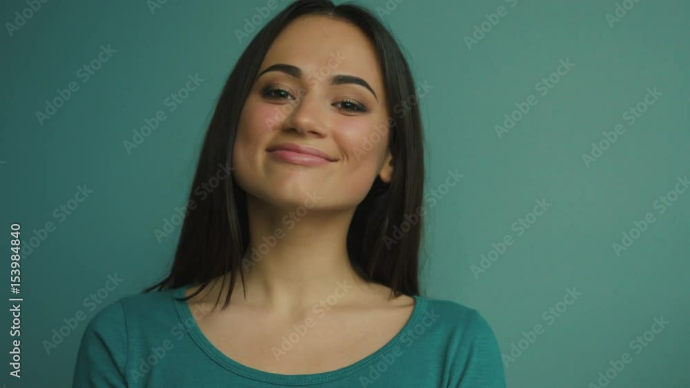 Portrait of serious beautiful woman looking at the camera and smiling. Blue background Portrait of serious beautiful woman looking at the camera and smiling. Blue background