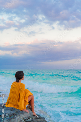 Young beautiful woman in sunset. Happy girl in dress in the evening on the beach