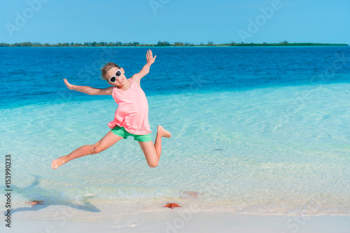 Adorable little girl having fun on the beach full of starfish on the sand
