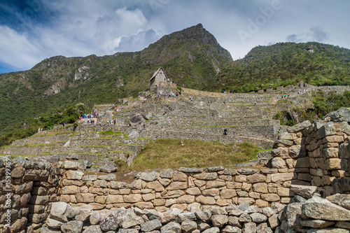 MACHU PICCHU, PERU - MAY 18, 2015: Tourists and a building called guardhouse at Machu Picchu ruins, Peru.