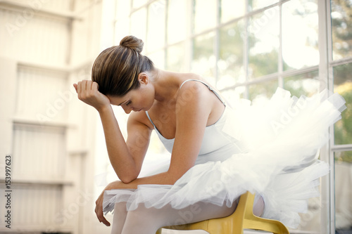 Mid adult ballerina sitting with her head in her hands.