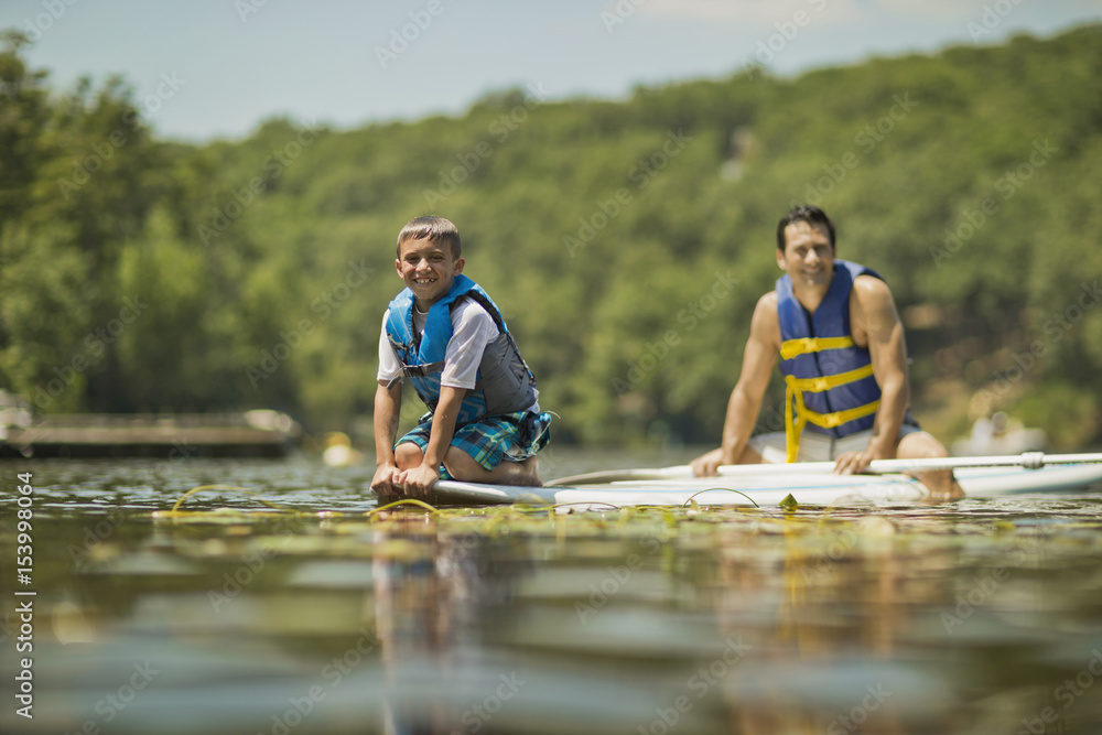 Father and son having fun paddleboarding on the river. Father and son having fun paddleboarding on the river.