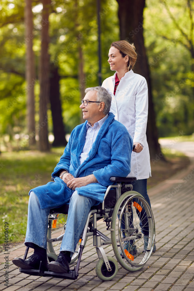 portrait of elderly man on wheelchair with nurse outdoor. portrait of elderly man on wheelchair with nurse outdoor.