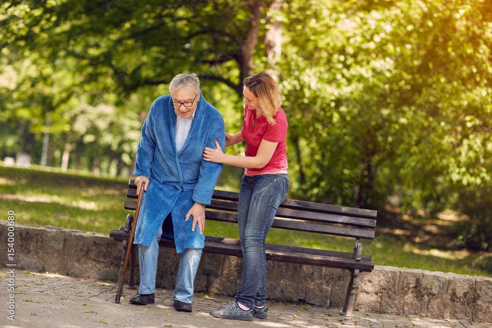 smiling daughter helping disabled father in park. smiling daughter helping disabled father in park.