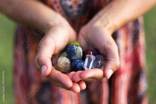 A young woman carefully holds a selection of vibrant gemstones as they reflect the soft sunlight. photo