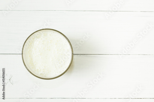 A glass of milk yogurt on a white wooden table.