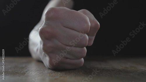 Fist of angry man beats on the table in slow motion