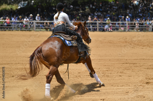 A rear view of a rider gallops on horseback on the sandy field
