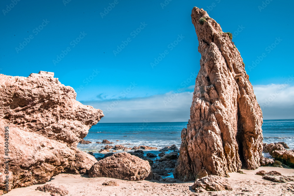 Fototapeta premium Large rocks on a rocky beach with a blue cloudy sky