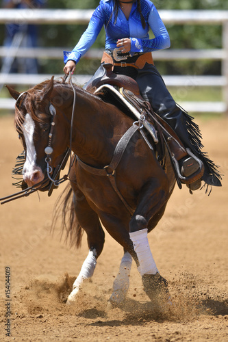 A front view of a rider twisting the horse on the spot on the sandy field  © PROMA