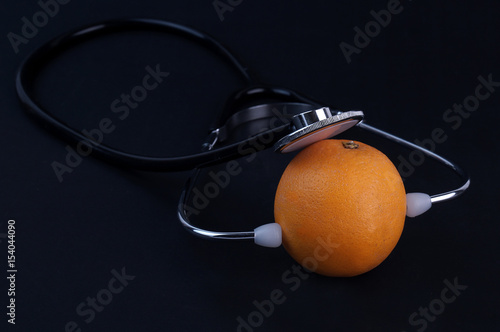 Stethoscope and orange on black background. Medical and Healthcare Concept.