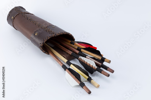 Different kinds of medieval handmade arrows with natural feathers in a handcrafted leather quiver isolated on white background