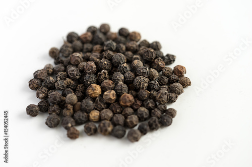 Black pepper seeds on a white background with some blurry effects (bokeh) applied. Organic seeds origin from Sarawak of Borneo, Malaysia.