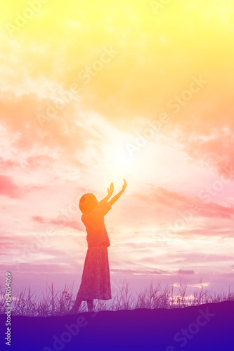 Silhouette of woman praying over beautiful sky background