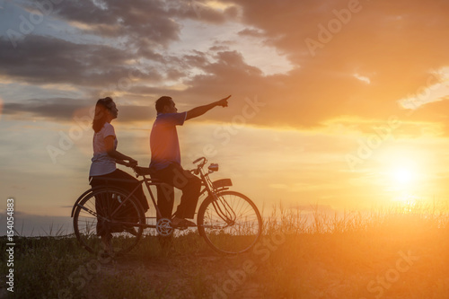 silhouette of sweet young couple in love happy time on bicycle