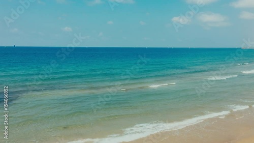 WIDE Handheld daytime shot of calm sea, waves splashing over the sandy shore. 4K color graded footage
 photo