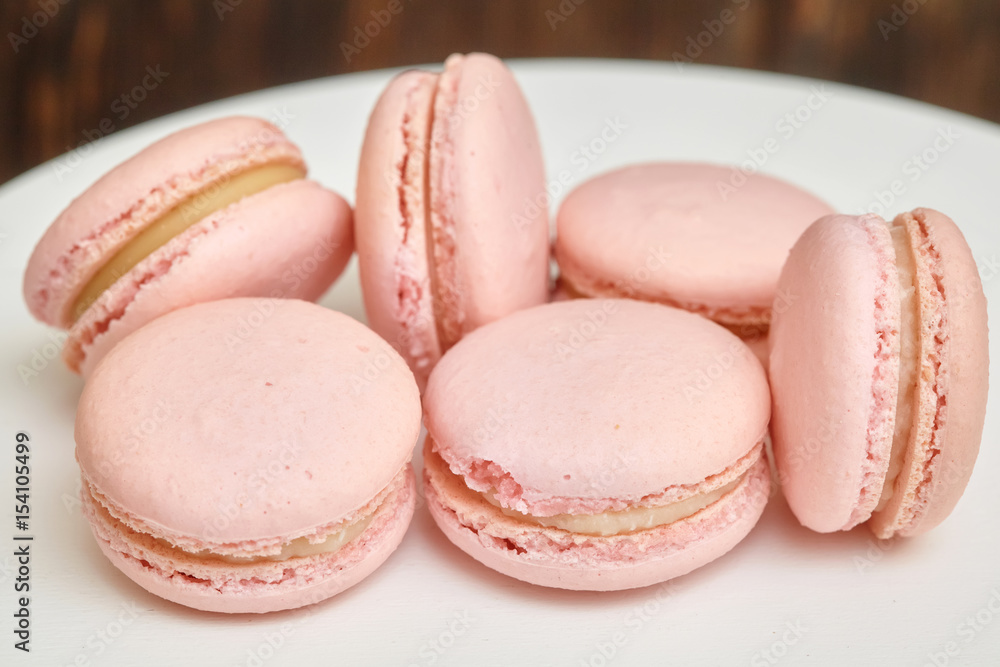 Pink macaroons on white stand on wooden background, homemade food Pink macaroons on white stand on wooden background, homemade food