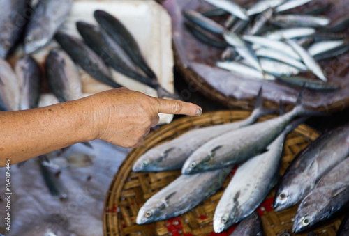 Close up of fisherman pointing at his fresh fishes at a market