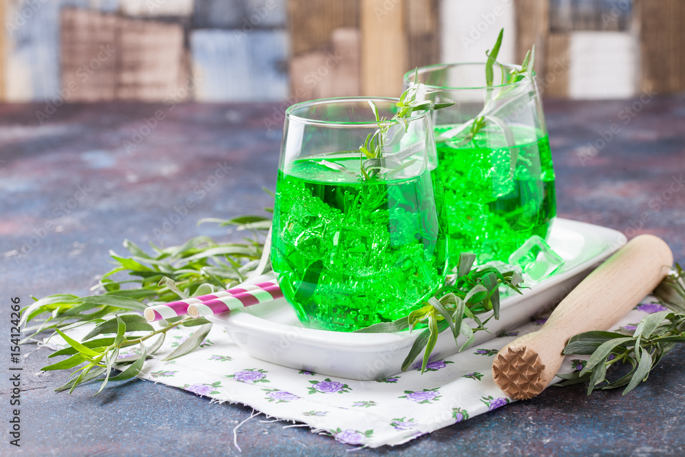 Drink from an estragon with ice in a glass on a table. Selective focus. Copy space