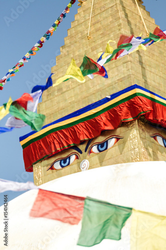 Closeup of the Buddha eyes of Boudhanath stupa surrounded by prayer flags in Kathmandu, Nepal. It is the largest stupa in Nepal and the holiest Tibetan Buddhist temple outside Tibet.