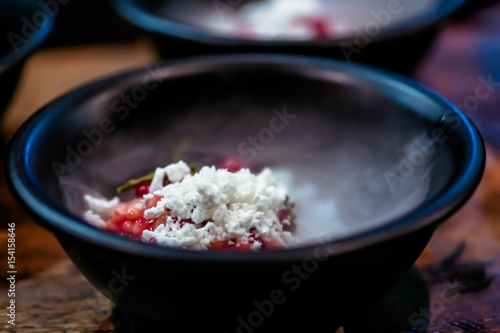 The dessert of berries with dry ice, in a black plate. Smoke from ice. Molecular cuisine.