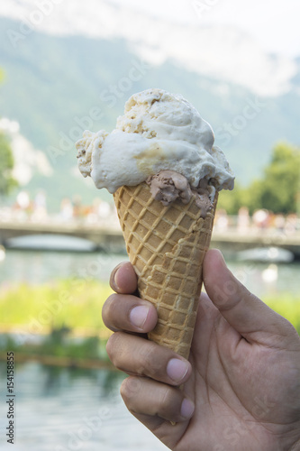 A Man Holding an Ice Cream Cone with a Scoop of Stracciatella and a Scoop of Chocolate in Summer in Annecy, France